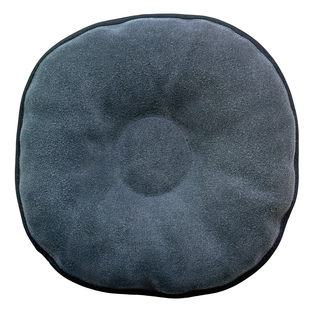 The back side of a round pillow-like shammy pad with a solid grey background.